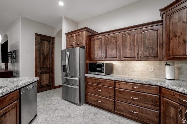 814 N High Ground Dr, Dammeron Valley, UT 84783 - kitchen featuring stainless steel appliances, arched walkways, light stone counters, and backsplash