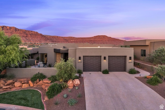 2549 W Sinagua Trl Unit 26, St George, UT 84770 - pueblo-style house with an attached garage, concrete driveway, a mountain view, and stucco siding