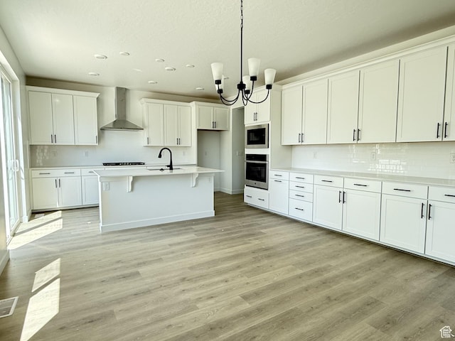 127 E Heron Ave Unit 808, Saratoga Springs, UT 84045 - kitchen featuring wall chimney range hood, stainless steel appliances, a sink, decorative backsplash, and white cabinets