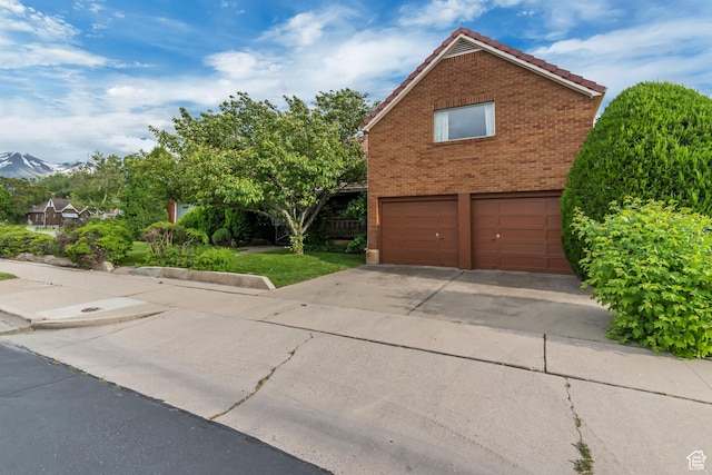 687 N Main St, Spanish Fork, UT 84660 - view of home's exterior featuring an attached garage, a tile roof, brick siding, concrete driveway, and a mountain view