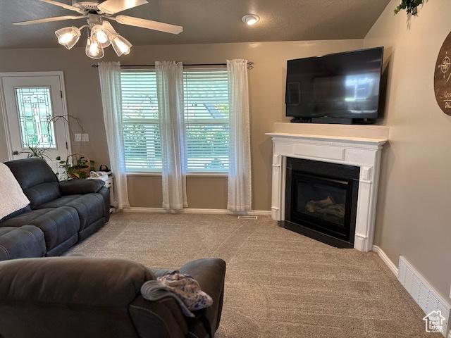 2025 E Skyline Dr, South Ogden, UT 84403 - carpeted living room featuring ceiling fan, plenty of natural light, a glass covered fireplace, and baseboards