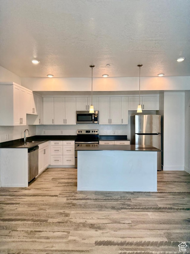 875 S Depot St Unit C211, Clearfield, UT 84015 - kitchen with stainless steel appliances, light wood-style flooring, dark countertops, white cabinetry, and a textured ceiling