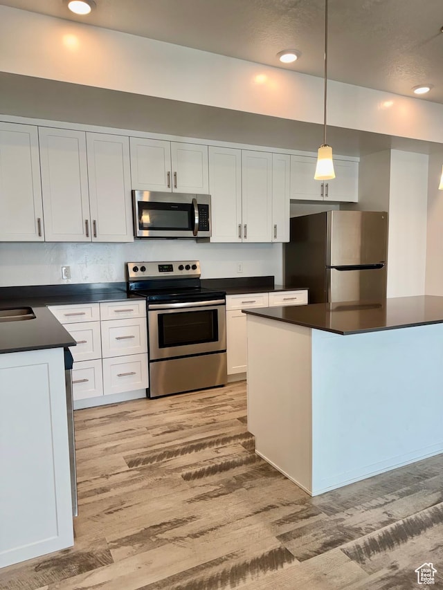 875 S Depot St Unit C211, Clearfield, UT 84015 - kitchen with appliances with stainless steel finishes, dark countertops, light wood finished floors, hanging light fixtures, and white cabinets
