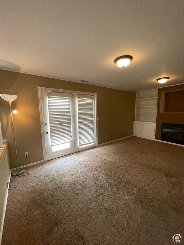 13778 S 2260 W, Riverton, UT 84065 - unfurnished living room with carpet, baseboards, a glass covered fireplace, and built in shelves