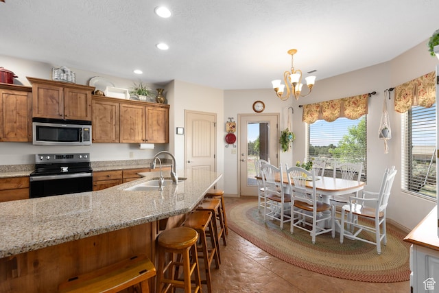 1374 E Big Pinion Ln, Apple Valley, UT 84737 - kitchen with black range with electric stovetop, stainless steel microwave, a sink, brown cabinets, and a kitchen bar
