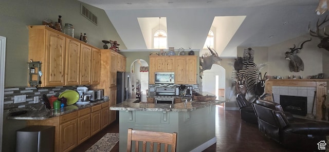 6897 S 4000 W, Benjamin, UT 84660 - kitchen featuring appliances with stainless steel finishes, arched walkways, stone countertops, decorative backsplash, and vaulted ceiling