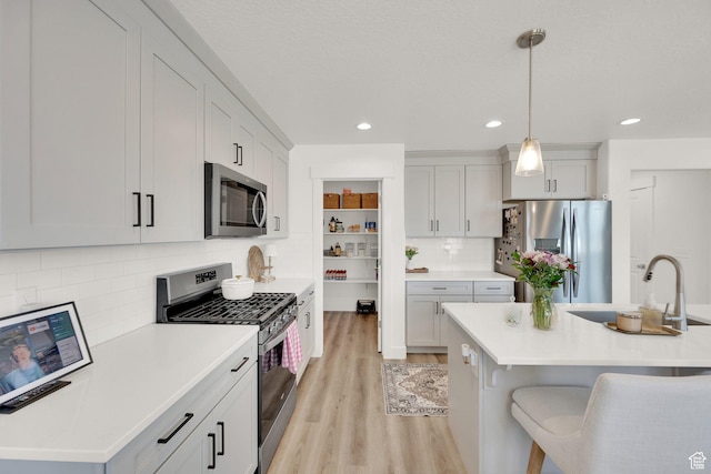 12297 S Boggs Way, Herriman, UT 84096 - kitchen with stainless steel appliances, light wood-type flooring, a sink, hanging light fixtures, and tasteful backsplash