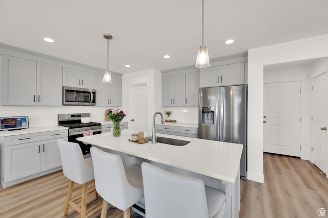 12297 S Boggs Way, Herriman, UT 84096 - kitchen with stainless steel appliances, a sink, decorative backsplash, light countertops, and light wood finished floors