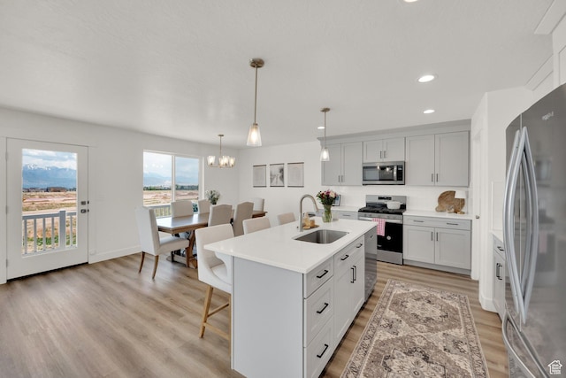 12297 S Boggs Way, Herriman, UT 84096 - kitchen featuring appliances with stainless steel finishes, a sink, light wood finished floors, a breakfast bar area, and light countertops