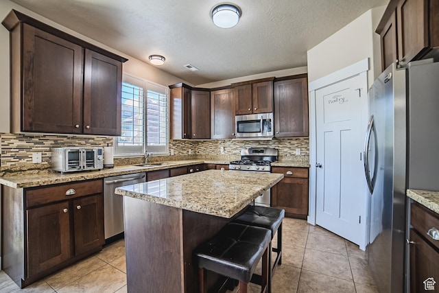 3907 W Tottori Dune Dr S, South Jordan, UT 84095 - kitchen with appliances with stainless steel finishes, a sink, tasteful backsplash, dark brown cabinetry, and a textured ceiling