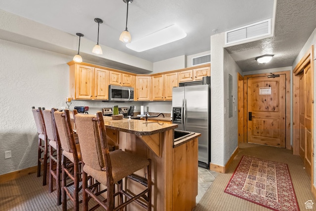 2669 Canyons Resort Dr Unit 304A, Park City, UT 84098 - kitchen with stainless steel appliances, a kitchen bar, a textured wall, baseboards, and light brown cabinets