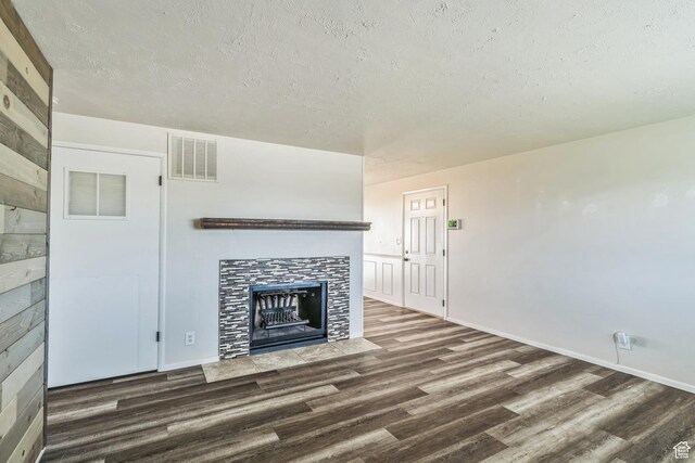 5230 S 5200 W, Kearns, UT 84118 - unfurnished living room featuring wood finished floors, a tiled fireplace, a textured ceiling, and baseboards