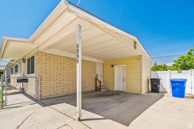 5230 S 5200 W, Kearns, UT 84118 - view of front facade featuring entry steps, concrete driveway, a gate, brick siding, and an attached carport
