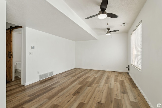 256 Jay Ln, Payson, UT 84651 - additional living space with light wood-style flooring, ceiling fan, a barn door, baseboards, and a textured ceiling