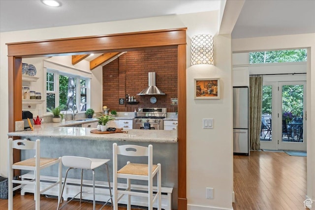 971 E Village Way, Alpine, UT 84004 - kitchen with appliances with stainless steel finishes, a sink, ventilation hood, wood finished floors, and a kitchen breakfast bar