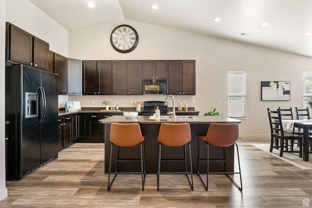 1135 Surrey Dr, North Salt Lake, UT 84054 - kitchen featuring black appliances, a kitchen breakfast bar, a sink, a center island with sink, and high vaulted ceiling