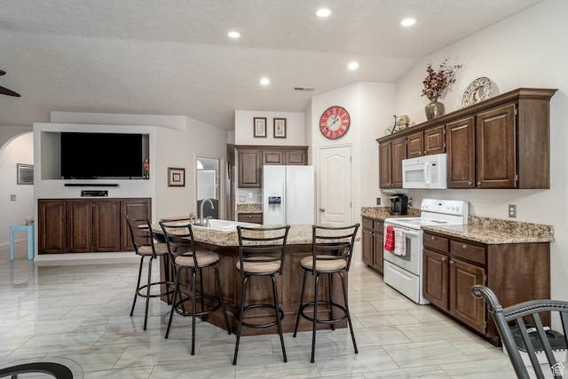 576 S Fiesta Dr, Ivins, UT 84738 - kitchen featuring white appliances, a breakfast bar, a center island with sink, light stone countertops, and recessed lighting