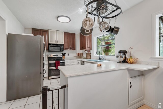 1789 N Stayner Dr W, Farmington, UT 84025 - kitchen featuring appliances with stainless steel finishes, a sink, a peninsula, and light tile patterned floors