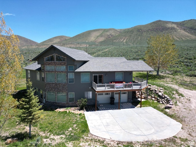 1940 E Shore Rd, Saint Charles, ID 83272 - rear view of house with a garage, a mountain view, concrete driveway, and stone siding