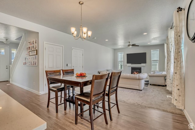 5058 W Blythswood Ln S, Herriman, UT 84096 - dining area featuring light wood-style floors, baseboards, a ceiling fan, a glass covered fireplace, and a textured ceiling
