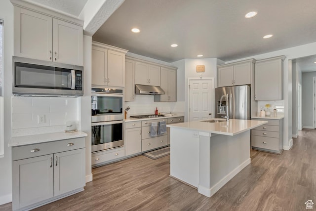 5058 W Blythswood Ln S, Herriman, UT 84096 - kitchen featuring appliances with stainless steel finishes, light wood-style floors, backsplash, light countertops, and gray cabinets
