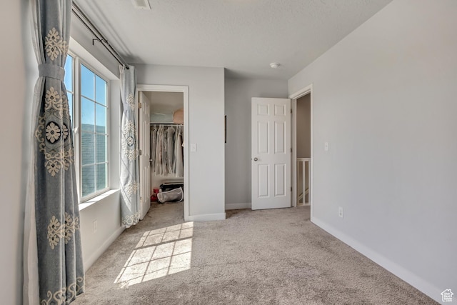 5058 W Blythswood Ln S, Herriman, UT 84096 - unfurnished bedroom featuring multiple windows, carpet flooring, baseboards, a textured ceiling, and a walk in closet
