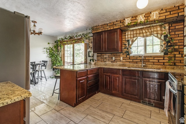 628 N Sir Philip Dr, Salt Lake City, UT 84116 - kitchen with a sink, a textured ceiling, a peninsula, plenty of natural light, and light stone counters