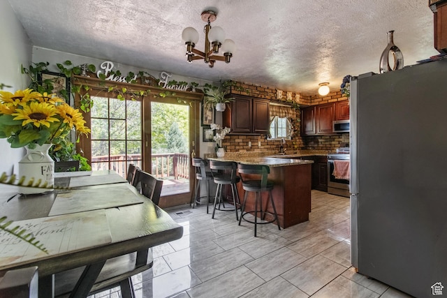 628 N Sir Philip Dr, Salt Lake City, UT 84116 - kitchen with stainless steel appliances, a peninsula, healthy amount of natural light, a textured ceiling, and a chandelier