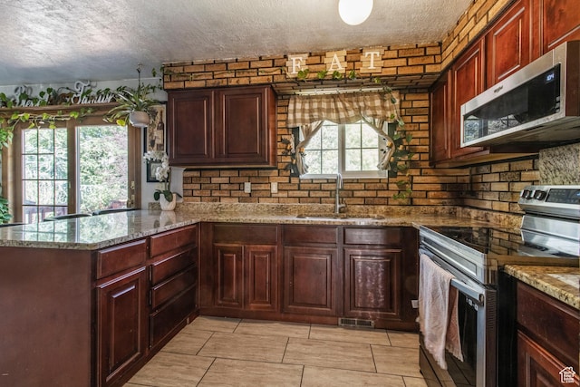 628 N Sir Philip Dr, Salt Lake City, UT 84116 - kitchen featuring appliances with stainless steel finishes, a sink, a textured ceiling, a peninsula, and light stone countertops
