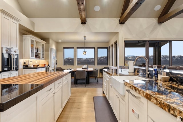 8982 N Mountain Crest Rd, Park City, UT 84098 - kitchen with a sink, stainless steel oven, butcher block countertops, beam ceiling, and light wood finished floors