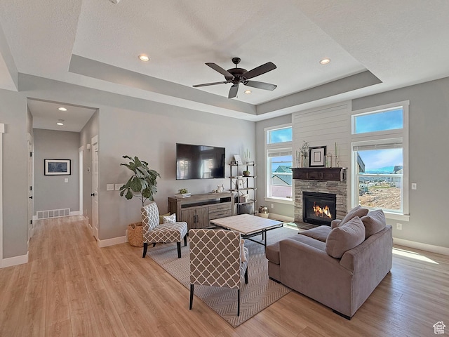 3723 N 500 E, North Ogden, UT 84414 - living area featuring a raised ceiling, baseboards, light wood-style floors, a ceiling fan, and a stone fireplace