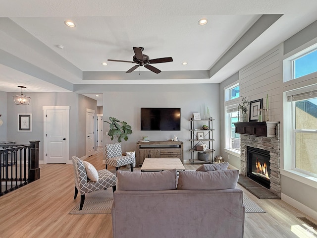 3723 N 500 E, North Ogden, UT 84414 - living area featuring light wood-type flooring, baseboards, a stone fireplace, a raised ceiling, and recessed lighting