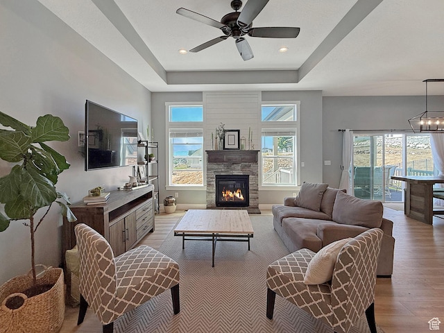 3723 N 500 E, North Ogden, UT 84414 - living room featuring light wood finished floors, ceiling fan, a fireplace, a tray ceiling, and recessed lighting