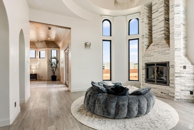 2836 S 2300th Cir E, St George, UT 84790 - living room featuring a fireplace, arched walkways, light wood-type flooring, baseboards, and lofted ceiling