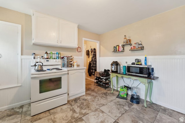 717 9th St, Ogden, UT 84404 - kitchen with electric stove, stainless steel microwave, wainscoting, white cabinetry, and light countertops