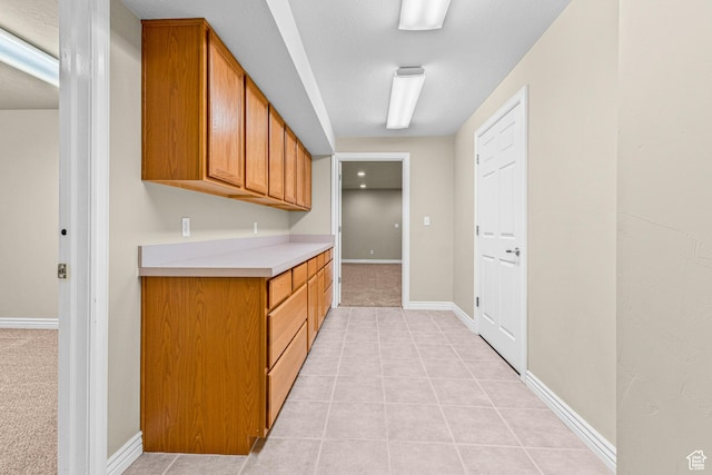 11815 S Cottage Side Way E, Draper, UT 84020 - kitchen featuring light countertops, brown cabinets, baseboards, light tile patterned floors, and light carpet