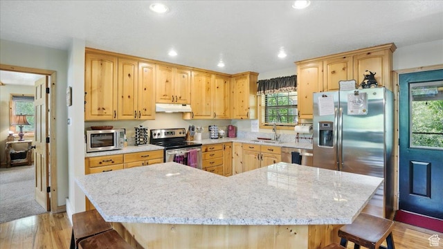 3786 Beaver Creek Rd, Kamas, UT 84036 - kitchen with appliances with stainless steel finishes, under cabinet range hood, a kitchen breakfast bar, light brown cabinetry, and light wood finished floors