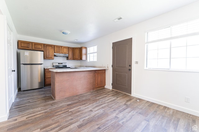 1560 W 300 S # 1, Vernal, UT 84078 - kitchen with appliances with stainless steel finishes, under cabinet range hood, brown cabinetry, wood finished floors, and a peninsula