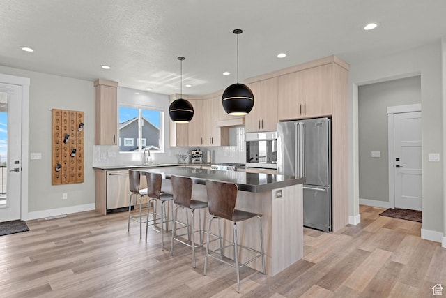 3877 N 425 E, North Ogden, UT 84414 - kitchen with stainless steel appliances, light brown cabinetry, a center island, a breakfast bar area, and light wood-style flooring
