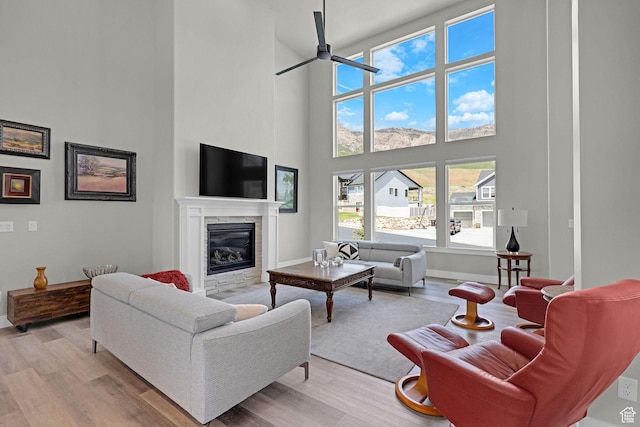 3877 N 425 E, North Ogden, UT 84414 - living area with a towering ceiling, a ceiling fan, a glass covered fireplace, light wood-style floors, and baseboards