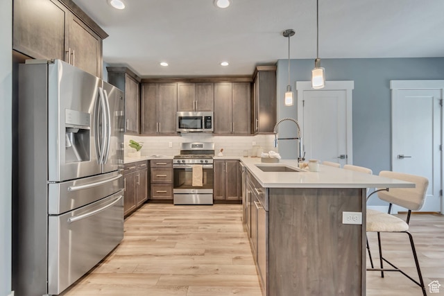 4237 S Birkhill Blvd, Murray, UT 84107 - kitchen with stainless steel appliances, a peninsula, a sink, a breakfast bar area, and light wood-style floors