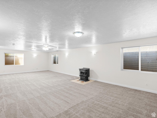 4912 W Rosewood Dr S, South Jordan, UT 84009 - spare room with a wood stove, a textured ceiling, a ceiling fan, carpet, and plenty of natural light