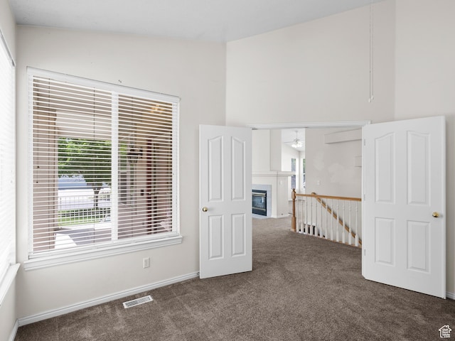 4912 W Rosewood Dr S, South Jordan, UT 84009 - empty room with carpet flooring, ceiling fan, a glass covered fireplace, baseboards, and a towering ceiling