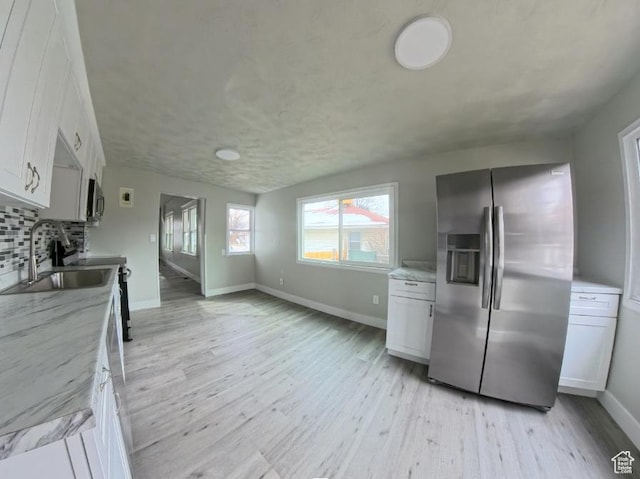 197 W Center St, Midvale, UT 84047 - kitchen with stainless steel appliances, a sink, light wood finished floors, decorative backsplash, and white cabinetry