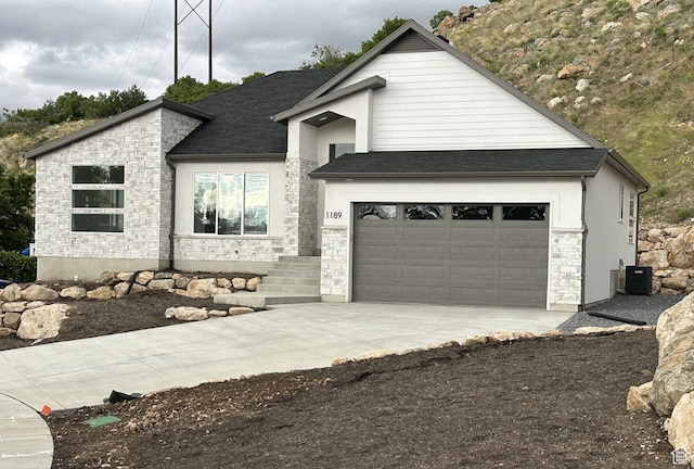 1189 E Benchview Dr, Ogden, UT 84404 - view of front of home featuring stone siding, concrete driveway, central AC unit, and roof with shingles