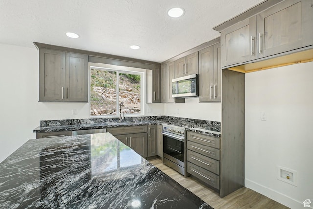 1189 E Benchview Dr, Ogden, UT 84404 - kitchen with stainless steel appliances, a sink, dark stone countertops, recessed lighting, and light wood-style floors