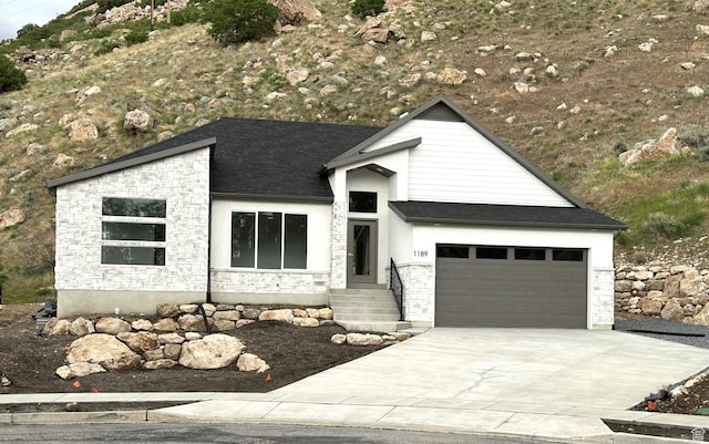 1189 E Benchview Dr, Ogden, UT 84404 - view of front of house with stone siding, concrete driveway, a garage, and roof with shingles