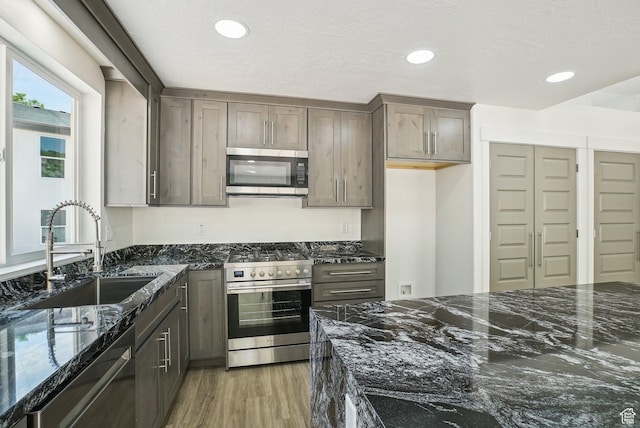 1189 E Benchview Dr, Ogden, UT 84404 - kitchen with appliances with stainless steel finishes, a sink, dark stone counters, light wood finished floors, and recessed lighting