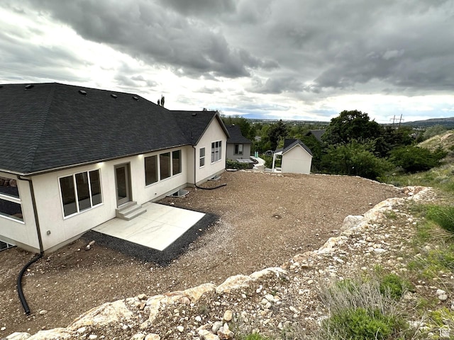 1189 E Benchview Dr, Ogden, UT 84404 - back of house featuring stucco siding, a shingled roof, and a patio