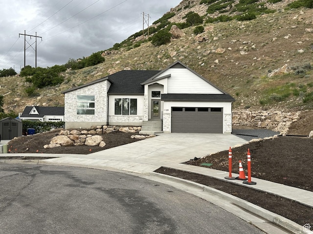 1189 E Benchview Dr, Ogden, UT 84404 - view of front of property with stone siding, concrete driveway, an attached garage, and a shingled roof